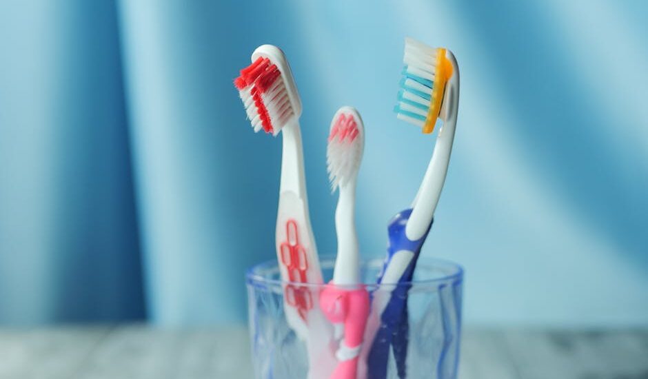 A trio of vibrant toothbrushes in a glass on a blue background, emphasizing dental hygiene.
