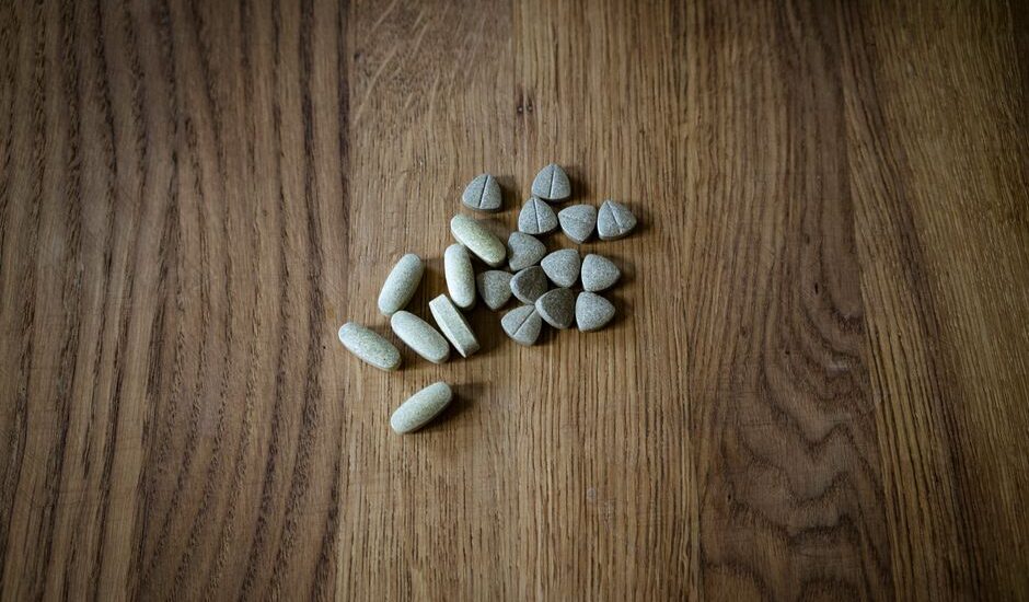 Assorted dog joint care supplement tablets and chews arranged on a wooden surface, illustrating options for canine joint health support.