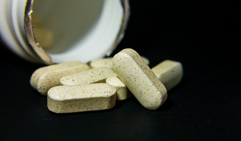 Several beige dog vitamin tablets spilled from an open bottle, illustrating the risks of dogs overdosing on supplements.