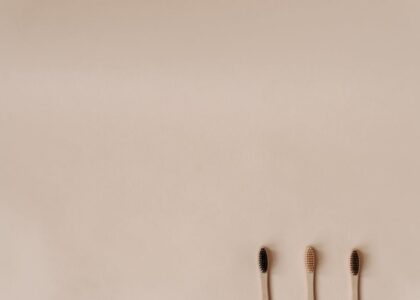 Three bamboo toothbrushes on a minimal beige background promoting eco-friendly oral care.