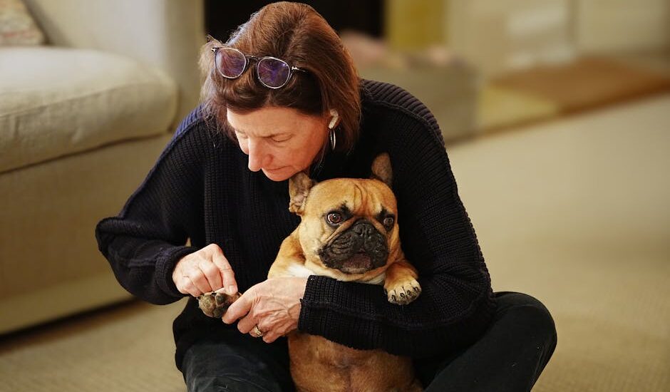A woman gently trims a dog's nails with an electric nail trimmer, demonstrating the process.