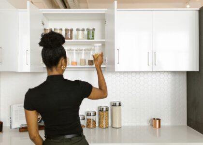 A person reaching for a clear container in a kitchen cabinet, showcasing dog food storage options.