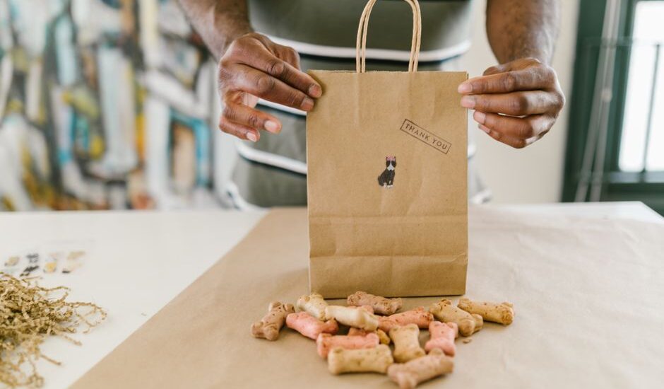 A person holds a thank you bag filled with colorful homemade dog treats, relating to the dog treat balls recipe.